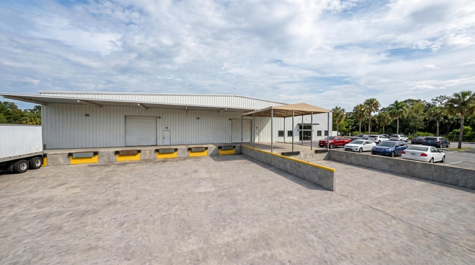 Dock apron and truck court with a trailer parked at a dock position and yellow dock bumpers.